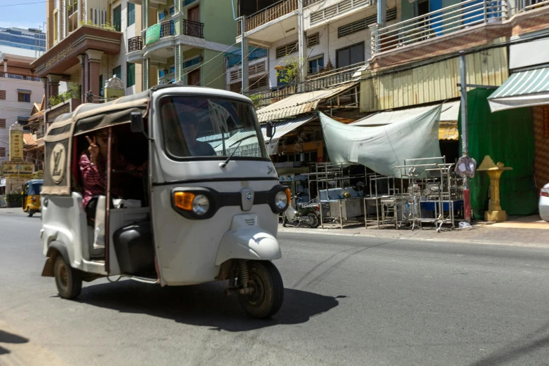 a white vehicle with open top driving down a street