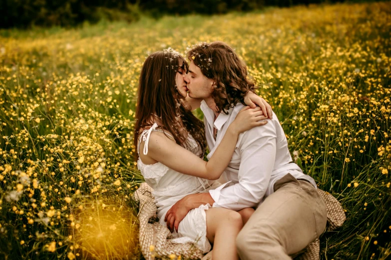 young couple kisses with flowers in the back ground