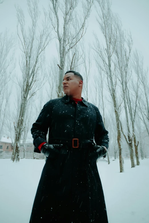 the man is dressed in a black coat and red gloves