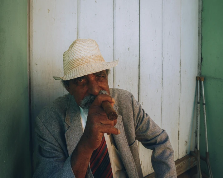 a man wearing a fedora is holding a pipe