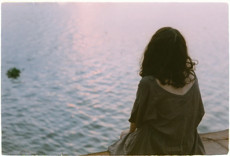 a woman is staring at the water as she waits for soing to come