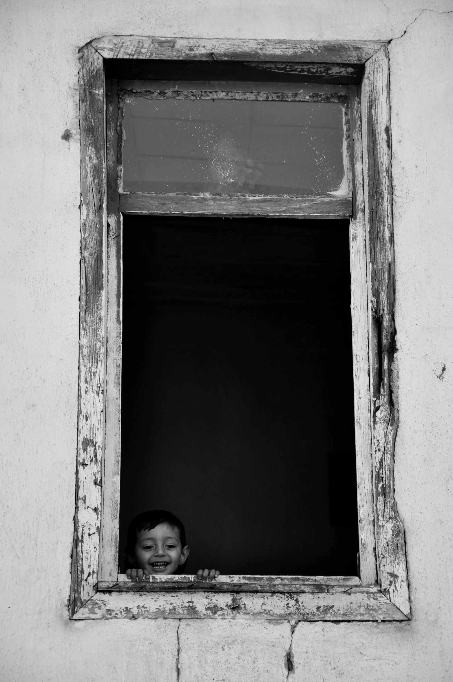 young child looking out the window from the inside of the building