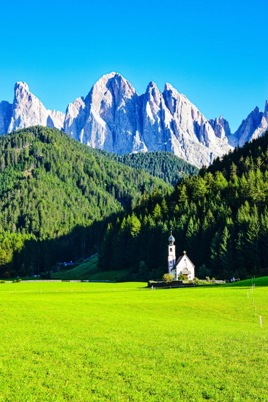 the church stands alone in the meadow in front of some mountains