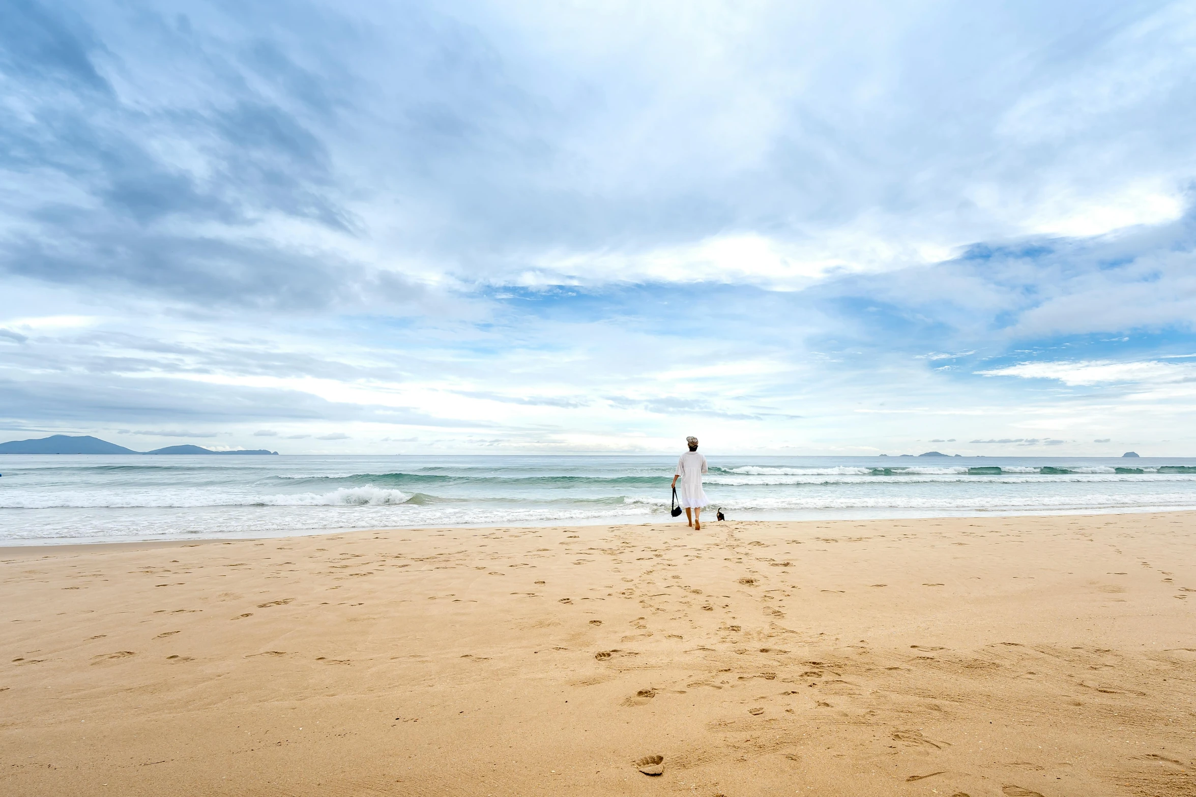 a man walking along the shore line near the beach