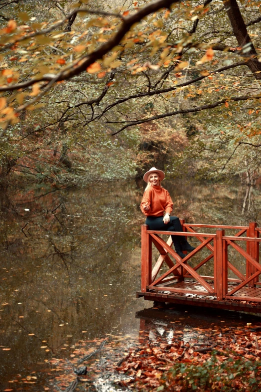 a woman standing on a bridge with leaves on the ground