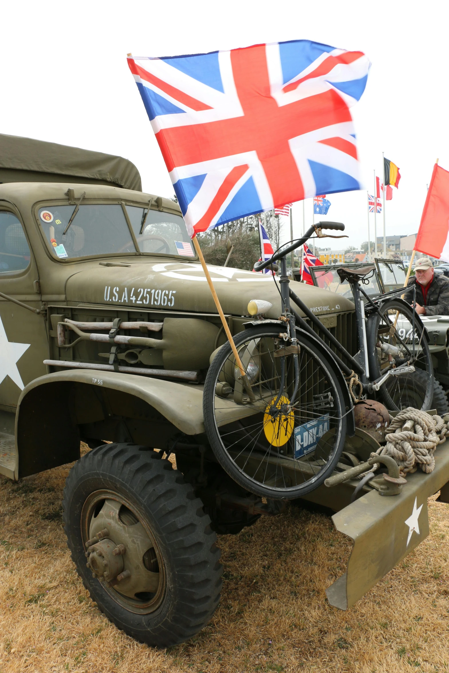 some old military trucks and one is holding an union jack