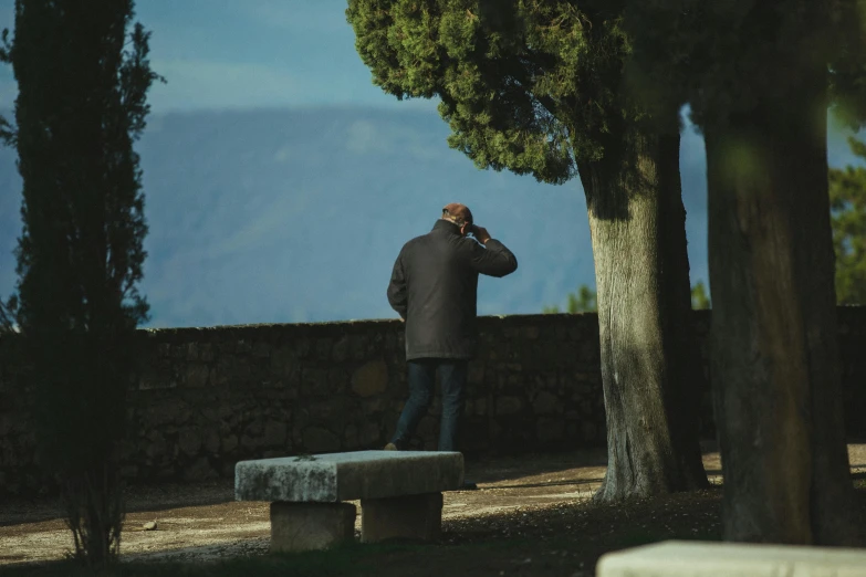 a man sitting on a bench while talking on his cell phone