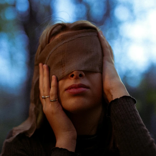 a woman wearing a blindfold holding her head