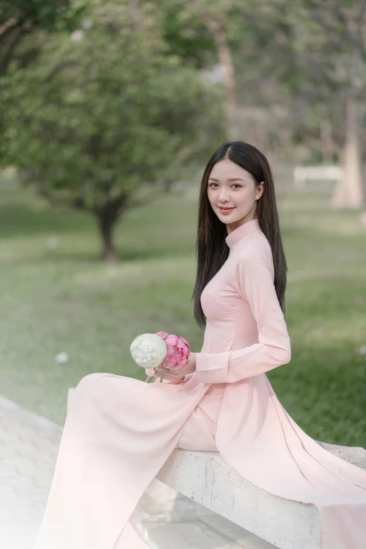 a woman in a pink dress sitting on a stone bench