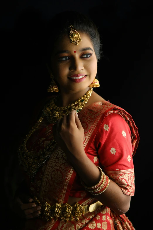 woman in red and gold traditional indian costume posing for a po
