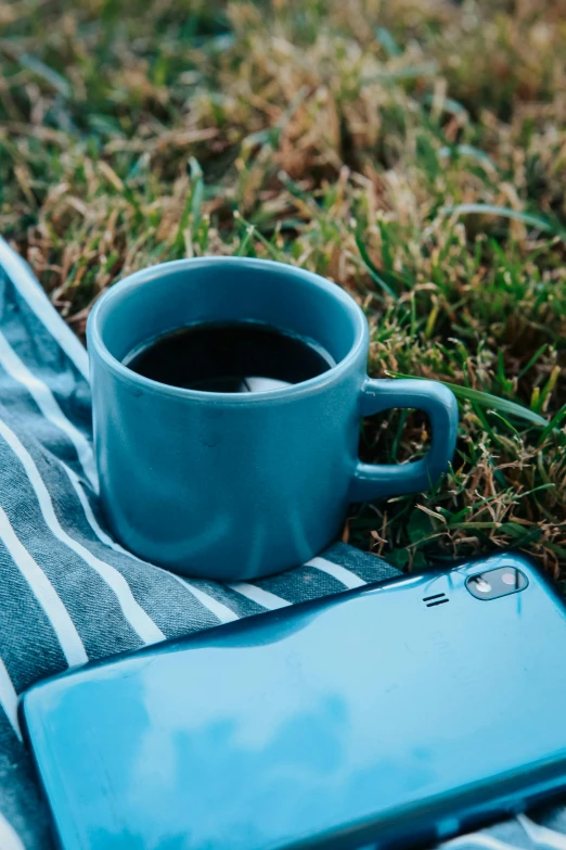 cup of coffee next to a cell phone on a towel