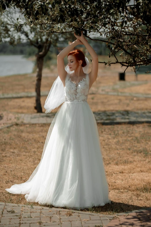 a woman posing outside in a white wedding dress