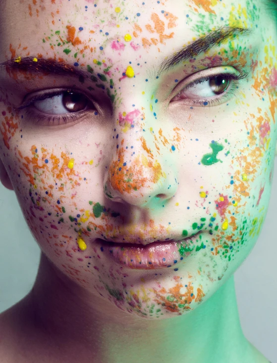 a woman's face covered in various colorful splatters