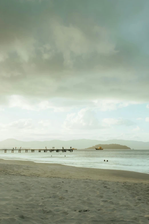 the beach area with people and boats is under a stormy sky