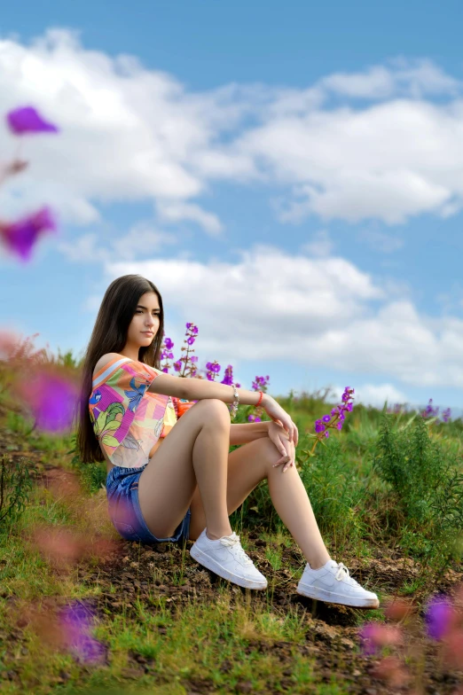 young woman sitting on the ground in grass and flowers