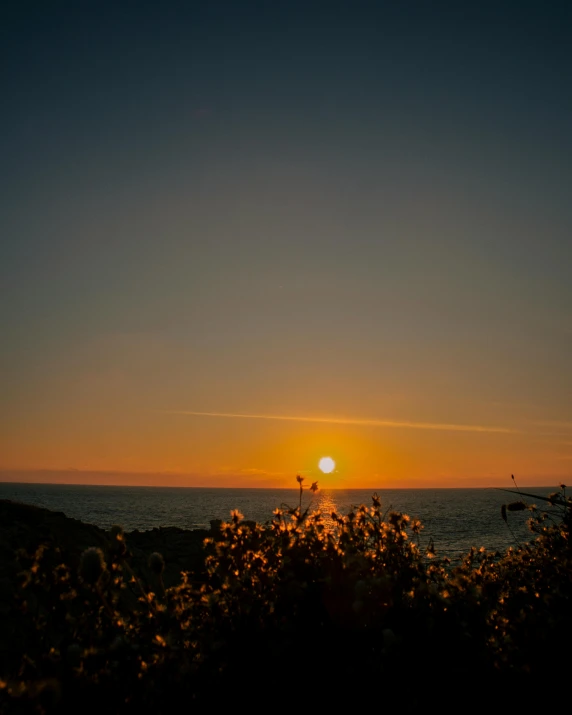 the setting sun over the ocean in the distance