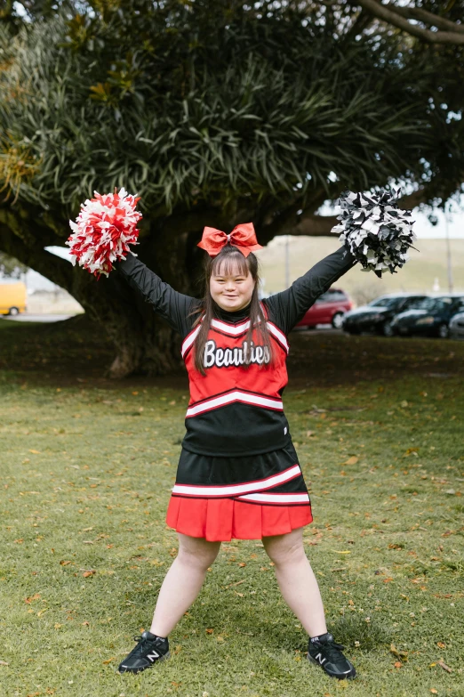 a girl is wearing a cheerleader outfit posing in front of trees