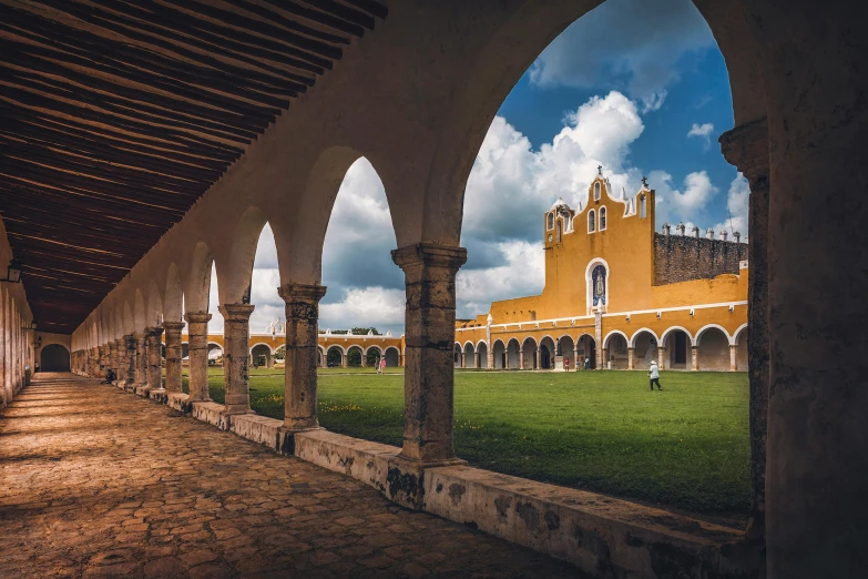 a building with arches in a courtyard filled with grass