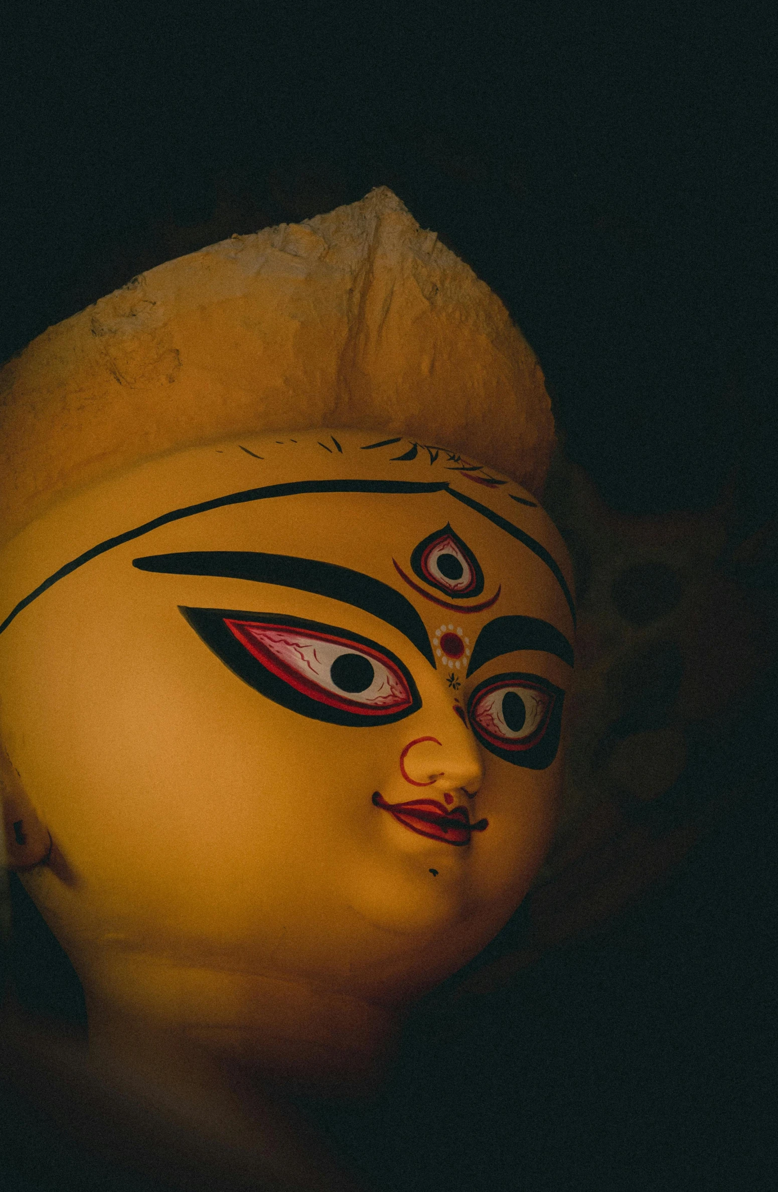 a large head statue sitting on top of a wooden pole