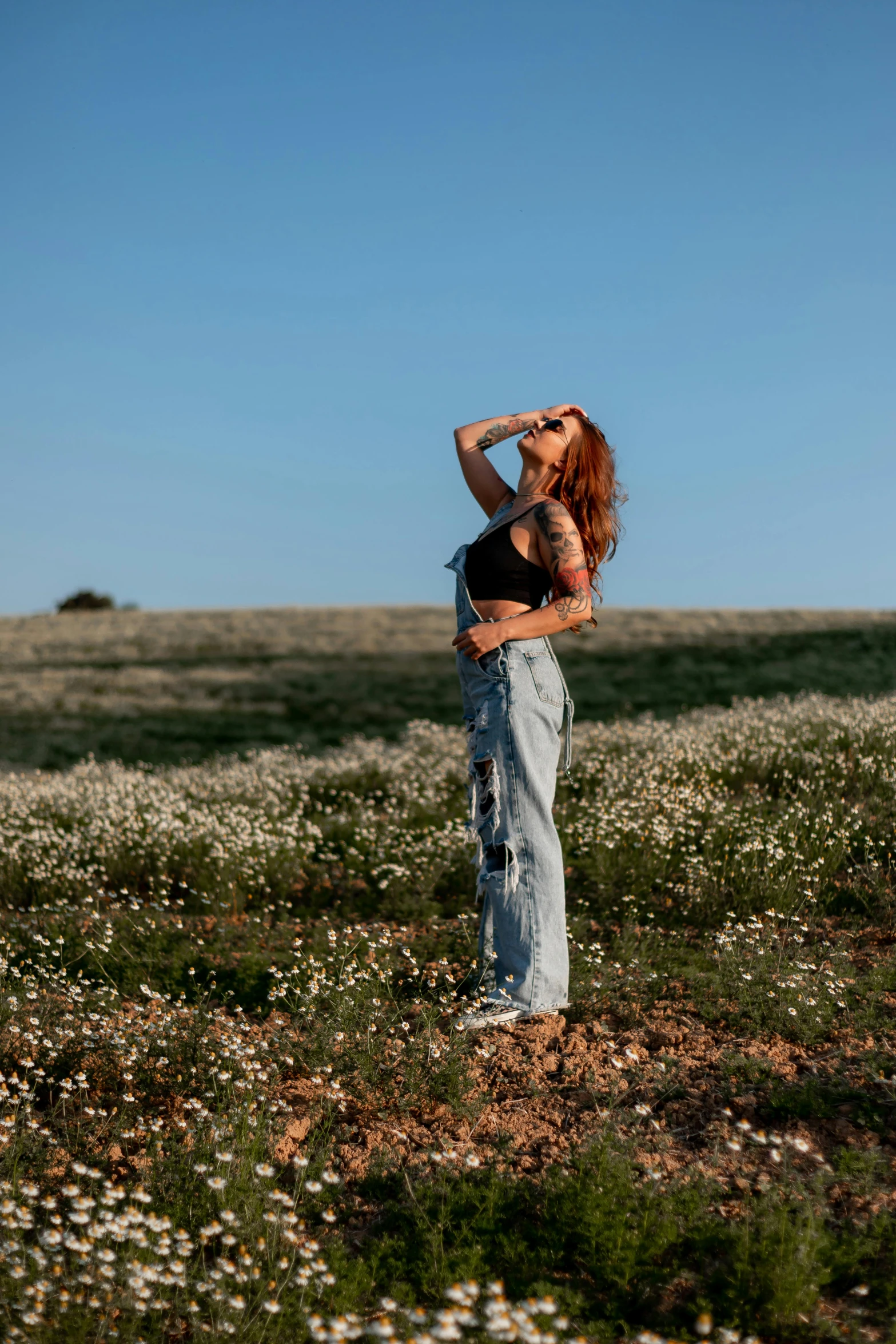 a woman standing in a field drinking from a bottle