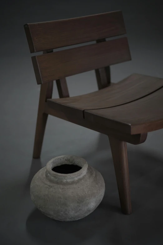 the chair is sitting next to the small vase