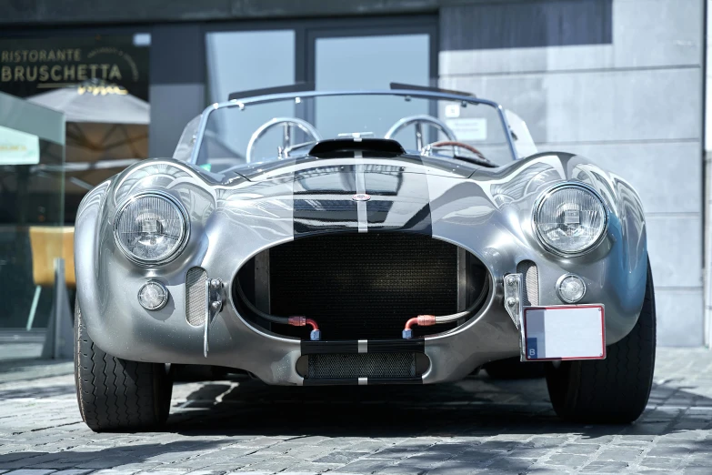 a silver race car sits on a sidewalk