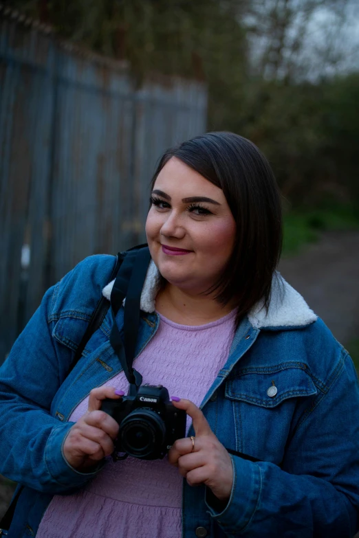 a smiling young lady holding up a camera