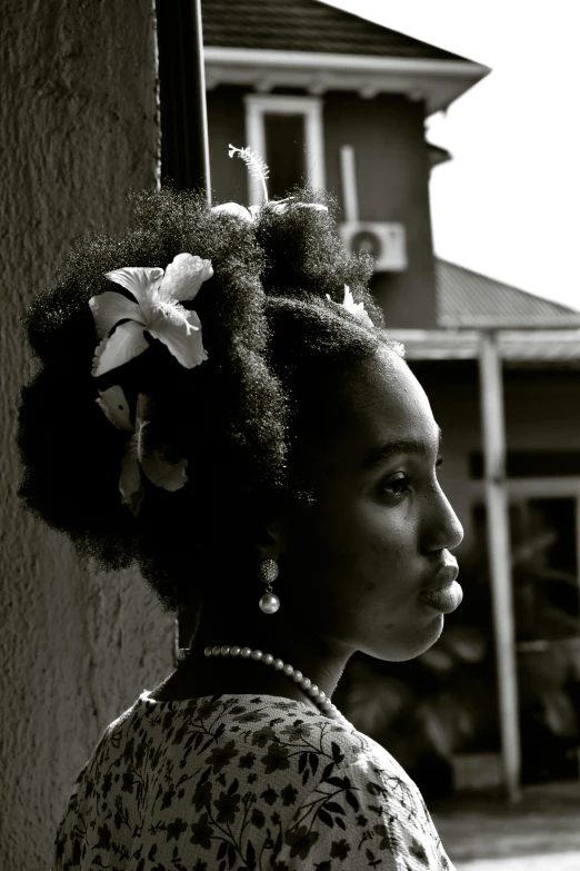 a woman looking out a window while wearing a flower in her hair