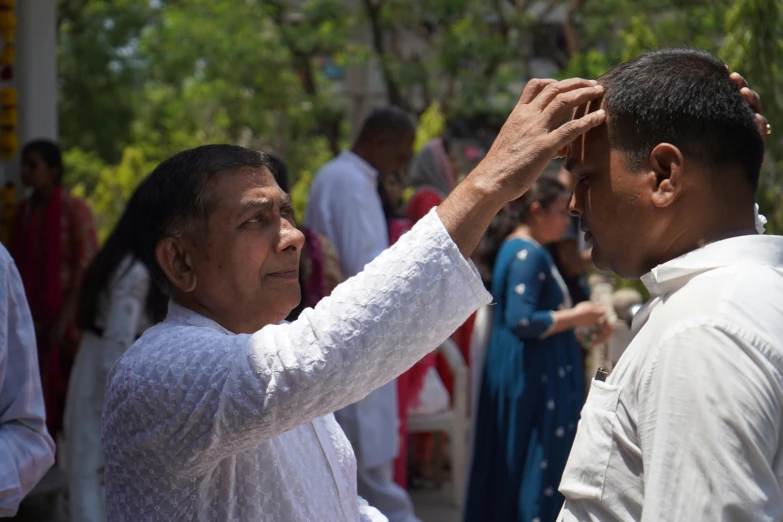 a man who is adjusting the ear of another person