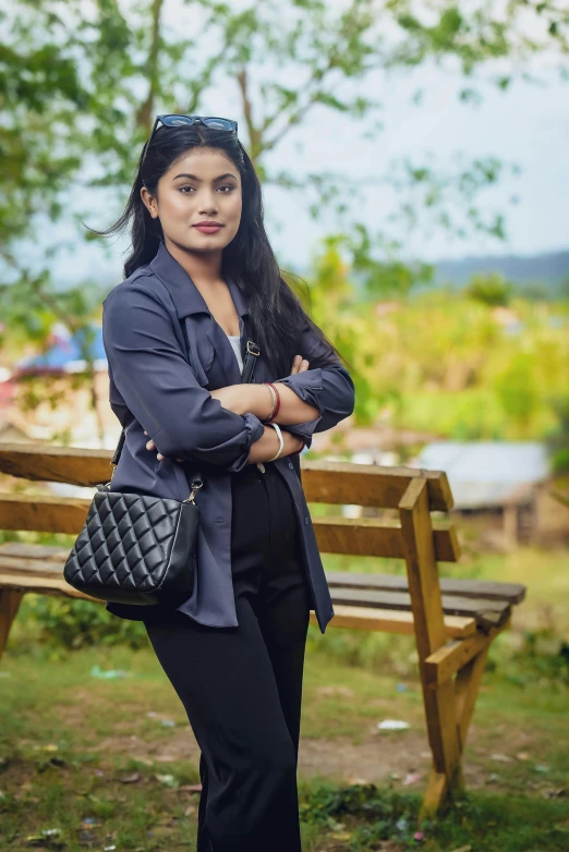 an indian woman poses for the camera while standing next to a wooden bench