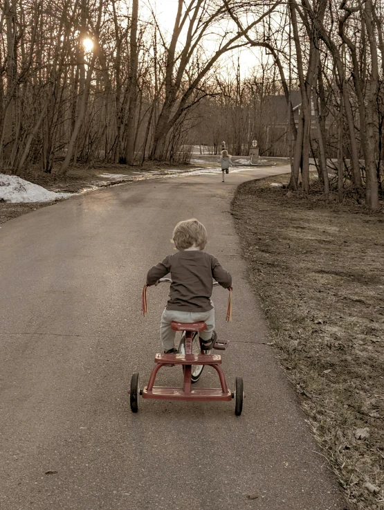 there is a young child riding in a tricycle on the street