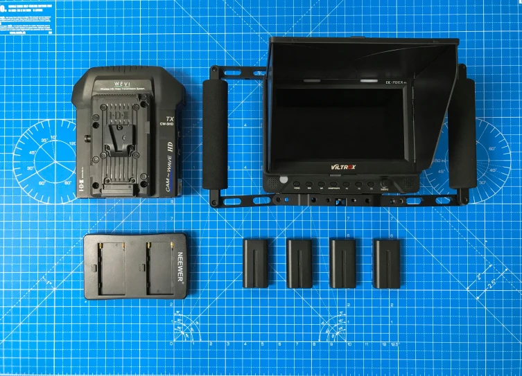 a table with multiple electronic equipment, including two small screen and several large batteries