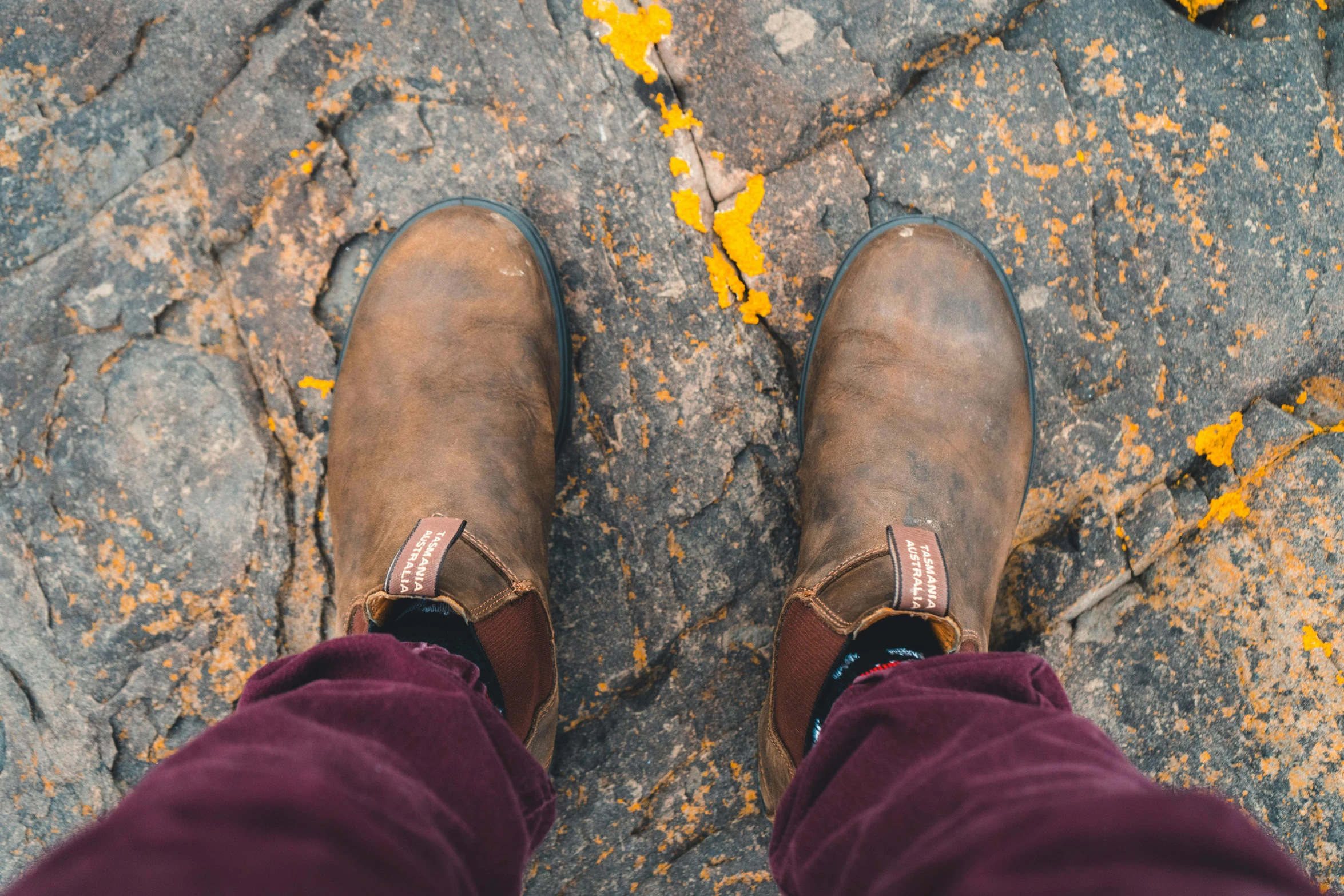 the feet of a person who is standing on a stone road