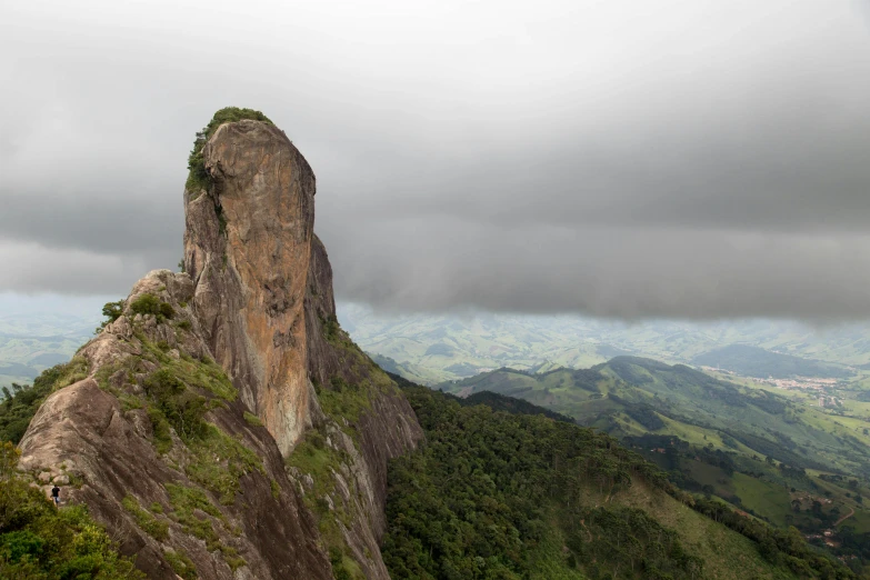 a large rock sits on a mountain with a cloudy sky