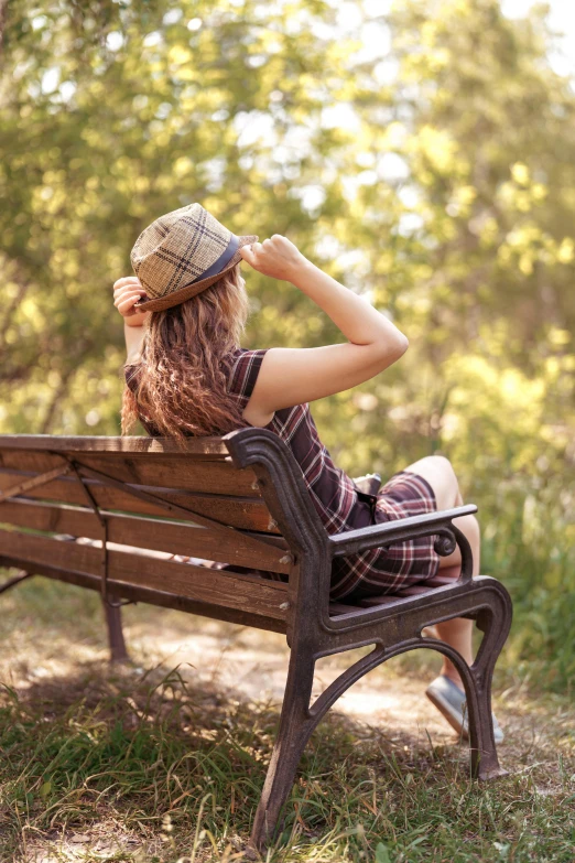 woman in dress sitting on park bench and stretching