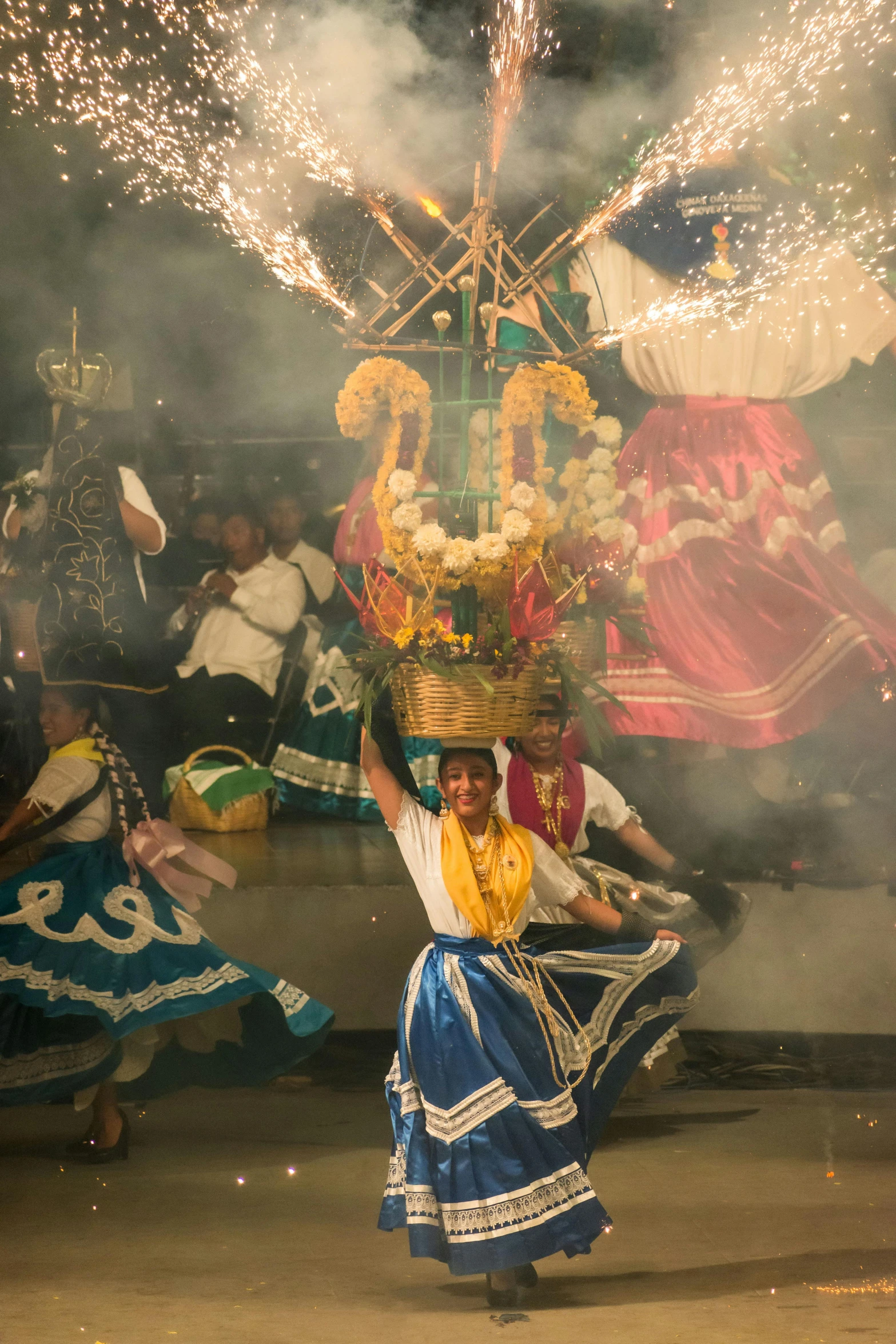 a woman in a traditional costume is holding up a basket with fireworks coming from the back