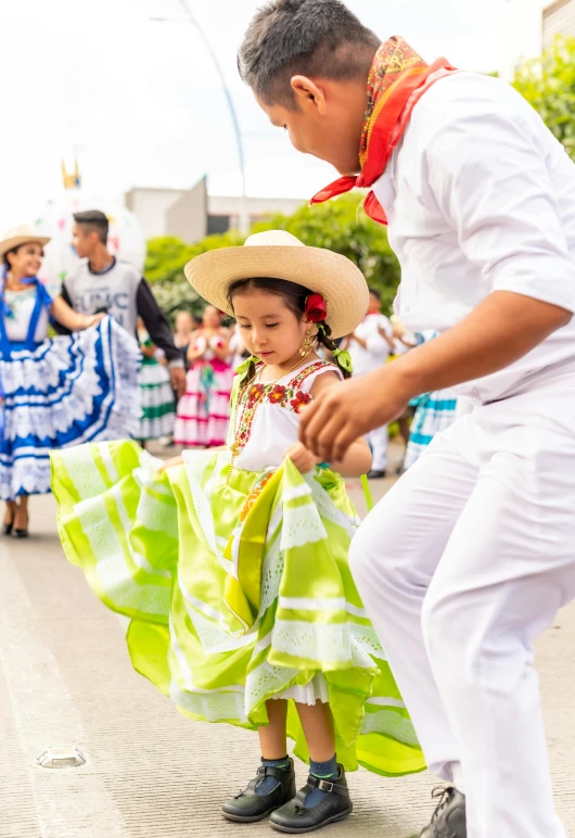 man dancing with his daughter and children in colorful costumes