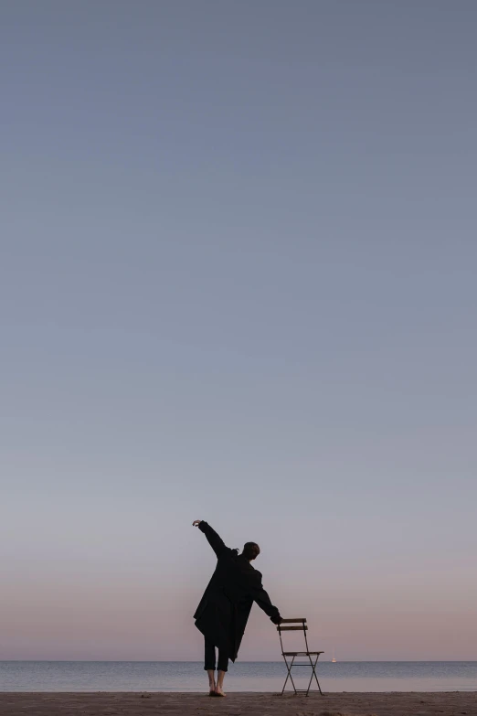 a woman in a long black coat throwing a kite