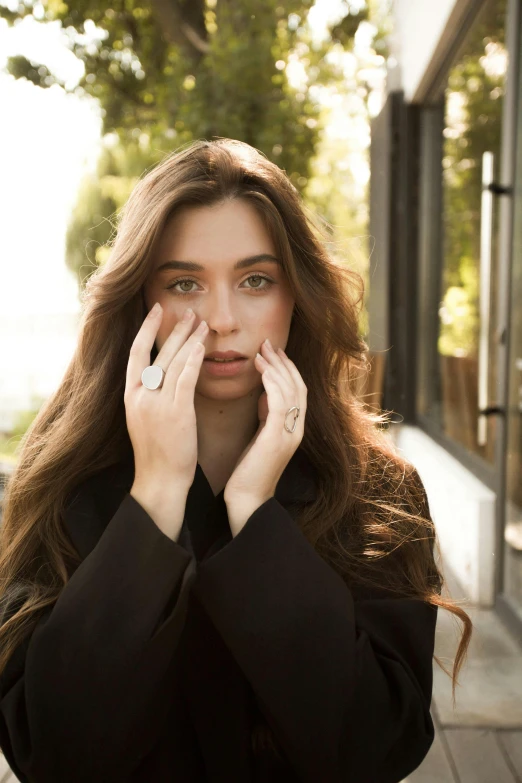 a woman is standing on the sidewalk covering her face with her hands