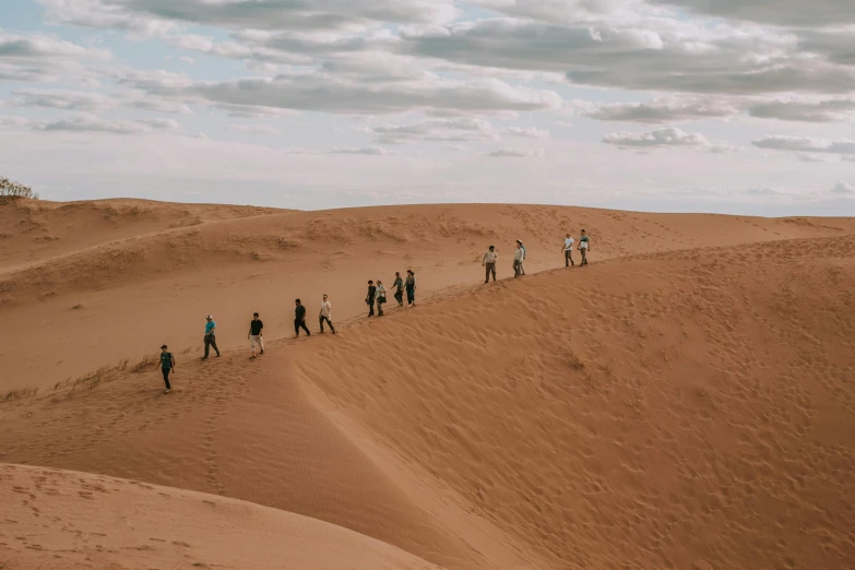 a line of people walking across the desert