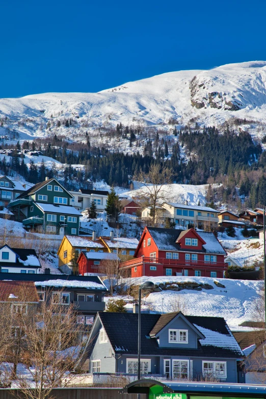 a snowy village with snow covered hills behind