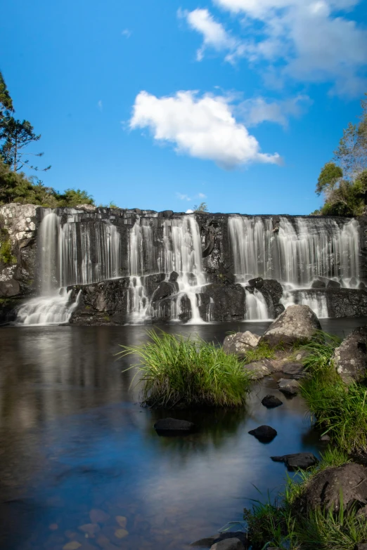 a small waterfall surrounded by rocks on a clear day