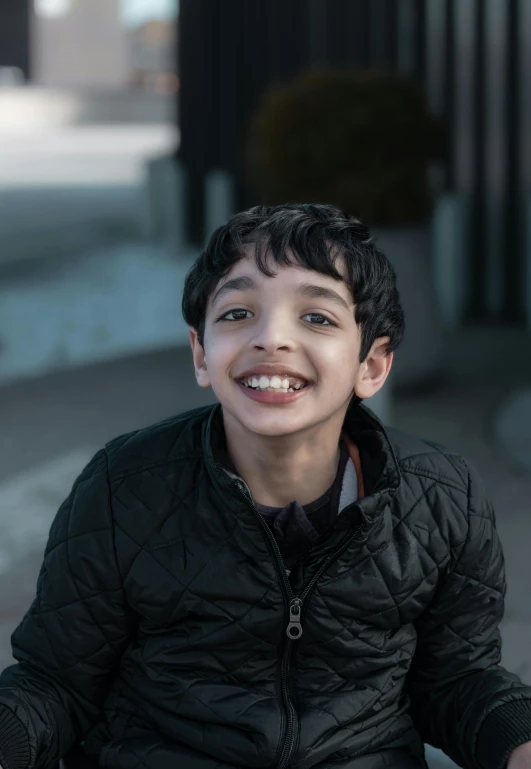 a little boy smiles in front of a building