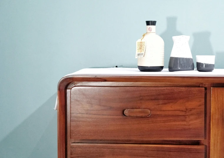 a bottle of alcohol, a glass and a napkin on a dresser