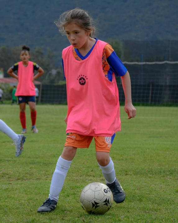 a little girl is kicking a soccer ball