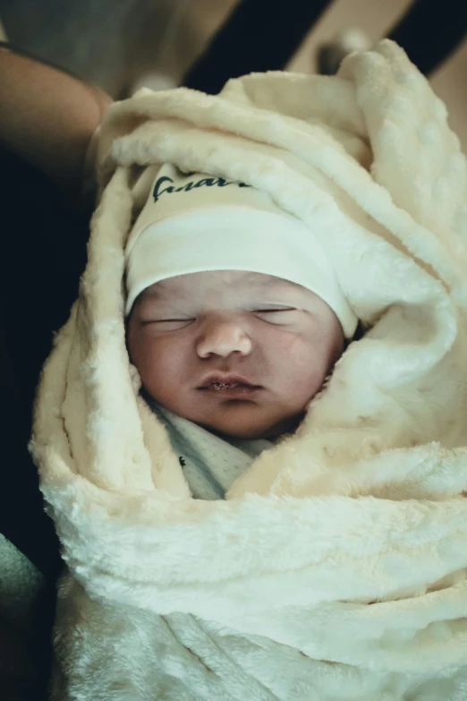 a sleeping baby wrapped in a blanket on top of a bed