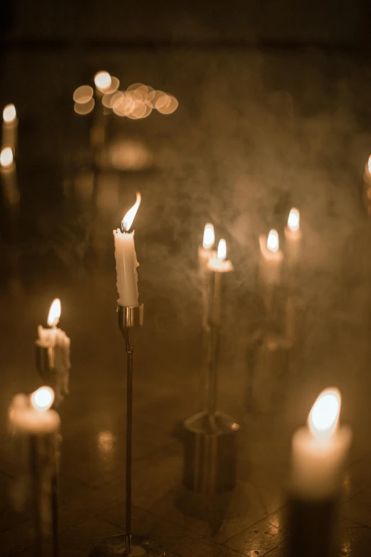 candles are burning in an empty room with one of the poles holding several lit candles