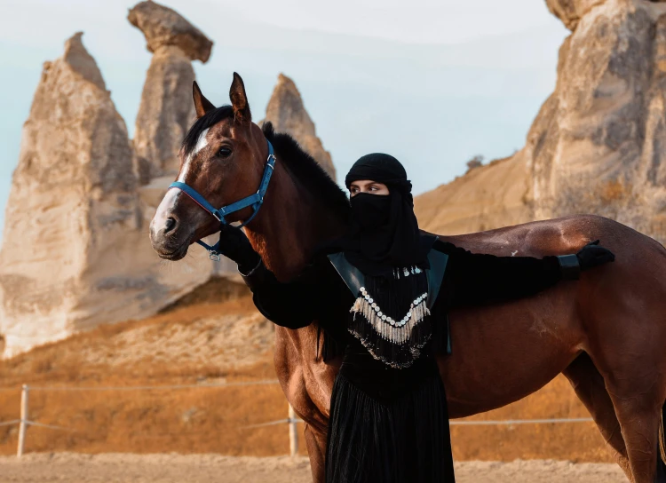 man in a burka holding the reins of a horse