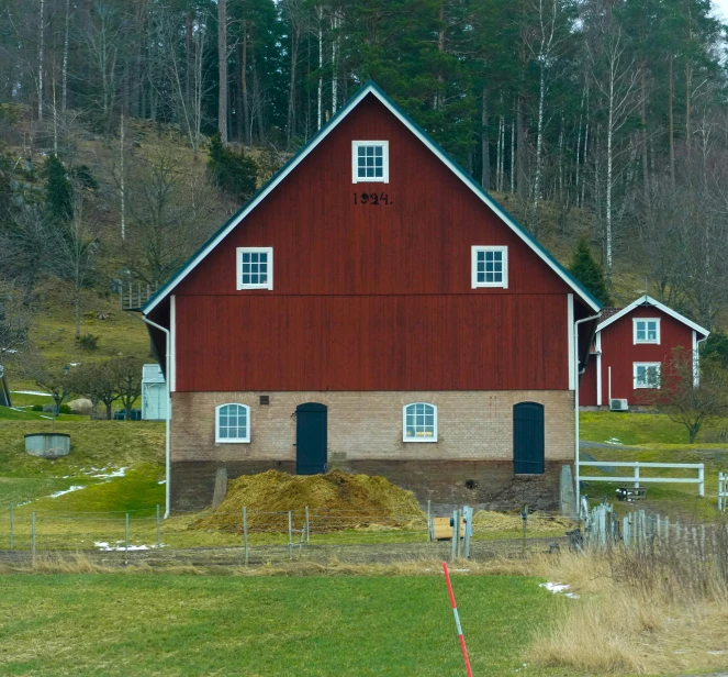 the red barn is in front of a row of trees