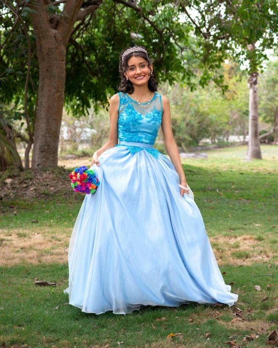 a woman in a blue gown is standing on the grass